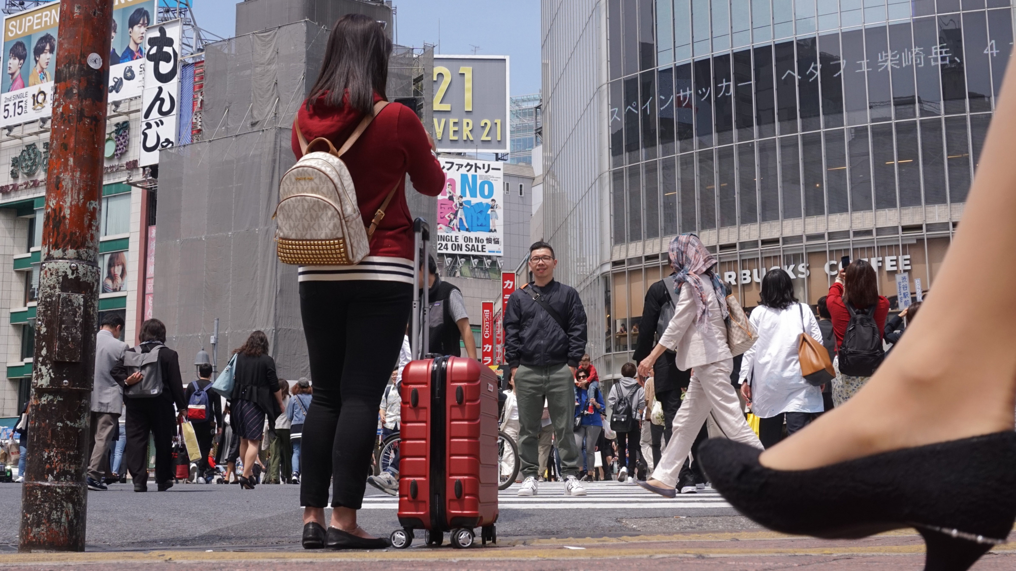 A woman takes a photo at Tokyo's famed Shibuya scramble crossing earlier this month. Many travelers end up sightseeing while dragging along their suitcases because it is often difficult to find an empty coin locker large enough to accommodate big pieces of luggage. | MAGDALENA OSUMI