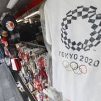 A T-shirt bearing the Tokyo Olympics logo hangs at a souvenir shop in the capital\'s Asakusa district. | KYODO