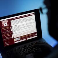A locked screen from a cyberattack by the Wannacry virus warns that data files have been encrypted on a laptop computer in May 2017. Japan has said it will develop its first-ever computer virus by next March as a defense measure against cyberattacks. | BLOOMBERG