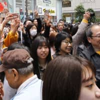 People watch a TV screen as the name of the next Imperial era is unveiled on a news program in Tokyo on April 1. | AP