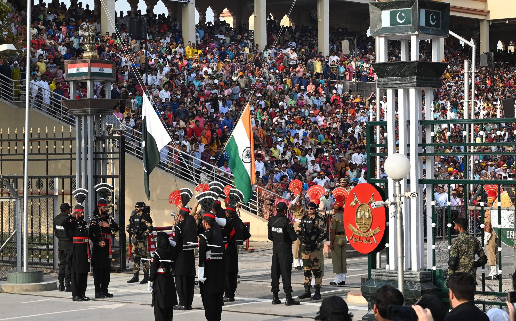 Pakistani Rangers (in black) and Indian Border Security Force personnel perform a flag-lowering ceremony at the Wagah border area between Pakistan and India on Saturday. | AFP-JIJI