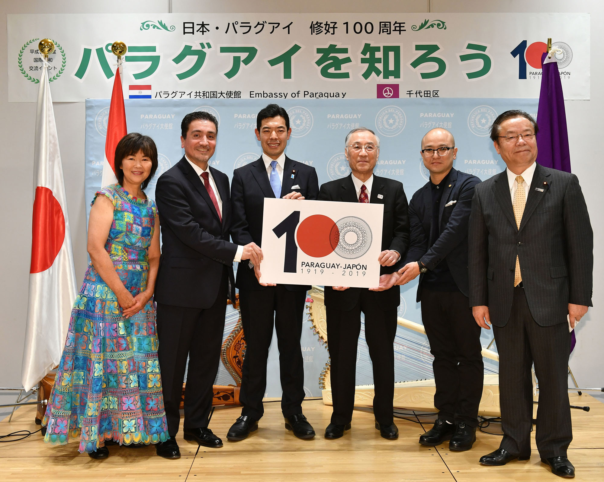 Paraguayan Ambassador Raul Florentin Antola (second from left) poses with (from left) nanduti (traditional embroidered lace) craftwork teacher Mie Elena Iwatani; Parliamentary Vice-Minister for Foreign Affairs Kiyoto Tsuji; Chiyoda Ward Mayor Masami Ishikawa; anniversary logo designer Tai Sato; and Secretary-General of the Japan-Paraguay Parliamentary Friendship League Koichi Tani during a reception to celebrate the 100th anniversary of diplomatic relations between Japan and Paraguay at Chiyoda City Hall on March 18. |  YOSHIAKI MIURA