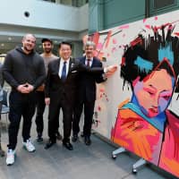 The Berlin-based street art group Tape That (first to third from left) poses with German Ambassador Hans Carl Freiherr von Werthern (right) and Bunkyo Ward Mayor Hironobu Narisawa at an opening ceremony debuting the group\'s artwork, made with adhesive tape, at the Bunkyo Civic Center in Tokyo. Tape That is in Japan to celebrate the 25th anniversary of sister city relations between Tokyo and Berlin. | YOSHIAKI MIURA