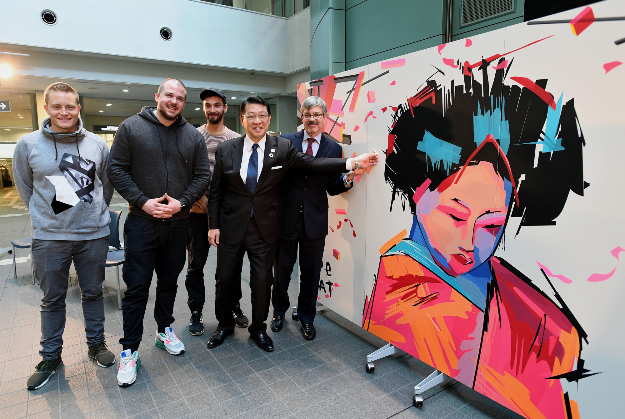The Berlin-based street art group Tape That (first to third from left) poses with German Ambassador Hans Carl Freiherr von Werthern (right) and Bunkyo Ward Mayor Hironobu Narisawa at an opening ceremony debuting the group's artwork, made with adhesive tape, at the Bunkyo Civic Center in Tokyo. Tape That is in Japan to celebrate the 25th anniversary of sister city relations between Tokyo and Berlin. |  YOSHIAKI MIURA