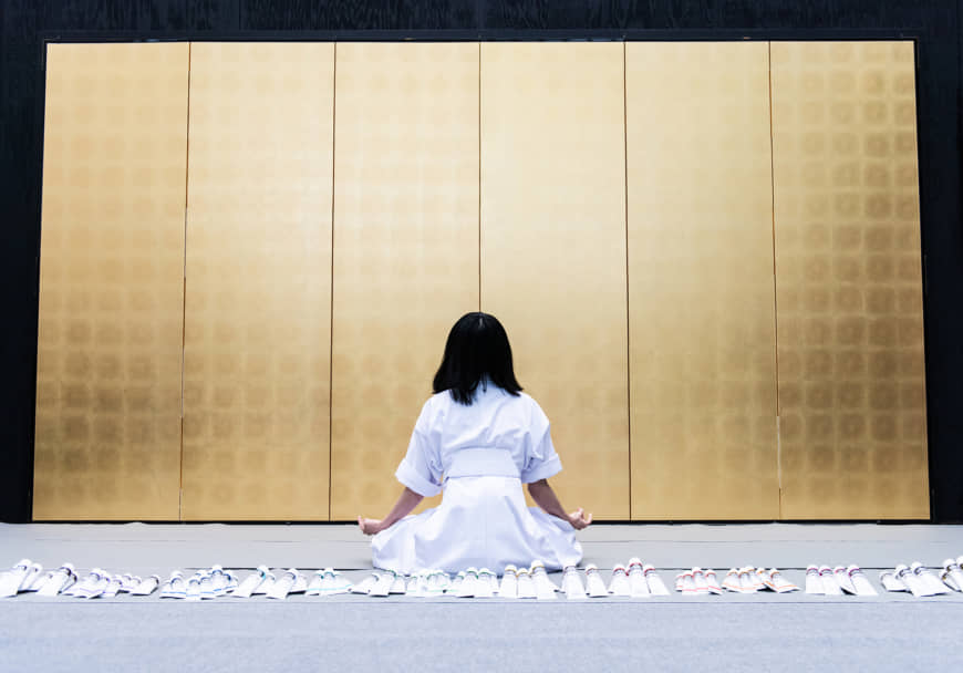 Miwa Komatsu sits cross-legged in front of a gilded folding screen on a stage at the Cleveland Museum of Art on May 11. | TATSUYA AZUMA