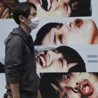 A man walks past an advertisement for Softbank in Tokyo. The telecoms firm\'s parent, SoftBank Group Corp., said Thursday its net profit in fiscal 2018 rose 35.8 percent to ¥1.41 trillion. | AP