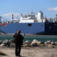 A man stands in view of Saudi cargo ship the Bahri Tabuk dcked at le Grand Port Autonome de Marseille\" GPAM in Port-Saint-Louis-du-Rhone, Tuesday in Marseille, France. According to a media report, the Saudi cargo ship is set to pick up munitions, rekindling criticism of weapons sales, which human rights groups say are being used in the devastating war in Yemen. | AFP-JIJI