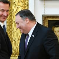 U.S. Secretary of State Mike Pompeo (right) and British Foreign Secretary Jeremy Hunt react during a joint news conference at the Foreign Office in central London Wednesday. | MANDEL NGAN / POOL / VIA REUTERS