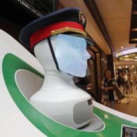 A family talks to passenger guide SEMMI, developed by German railway company Deutsche Bahn AG, on Wednesday. SEMMI is one of two artificial intelligence robots that East Japan Railway Co. deployed at a Tokyo Station information desk as part of a trial through May 31. | KYODO