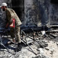 A wounded fighter loyal to Libya\'s U.N.-backed government (GNA) walks in front of a house burned during clashes with troops loyal to Khalifa Hifter in the Wadi Rabiya neighborhood on the outskirts of Tripoli Tuesday. | REUTERS