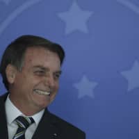Brazilian President Jair Bolsonaro smiles during an event at the Planalto Presidential Palace in Brasilia Tuesday. Bolsonaro convened a meeting of top ministers to discuss the ongoing situation in Venezuela. | AP