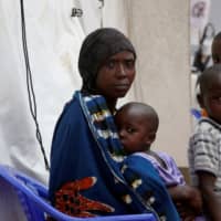 A Congolese woman and her children who are suspected Ebola patients sit at the Ebola treatment center in Butembo in the Democratic Republic of Congo in March. | REUTERS