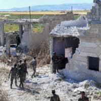 Syrian regime forces near a damaged building at the entrance of the town of Kafr Nabuda, in the north of the Syrian Hama province, on Sunday. | AFP-JIJI