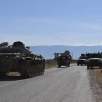 Syrian regime military vehicles drive toward Kafr Nabuda in the north of the Syrian Hama province on Sunday. | AFP-JIJI