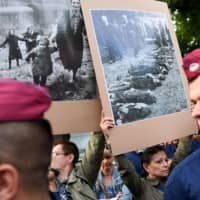 Anti-fascist sympathizers hold historical photos of the 20th century as new Hungarian far-right group, the Our Homeland Movement and their sympathizers, members of the National Legio, protest during a demonstration against the Roma community in Torokszentmiklos, about 130 km east of Budapest, on Tuesday. | AFP-JIJI