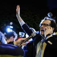 Jerome Triomphe (left), one of the two lawyers of the parents of Vincent Lambert, a quadriplegic man who has been in a vegetative state for the last decade, celebrates in Paris as he receives the news by the Paris Court of Appeal that ordered the restoration of the treatments to keep the 42 years old man alive, as they take part in a white march Monday. | AFP-JIJI