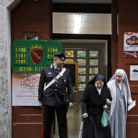 A Carabiniere (Italian paramilitary police) officer looks at nuns as they leave a polling station after voting for the European Parliament elections, in Rome Sunday. | AP
