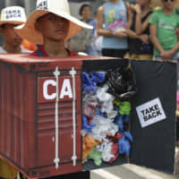 Filipino environmental activists wear a mock container vans filled with garbage to symbolize the 50 containers of waste that were shipped from Canada to the Philippines two years ago as they hold a protest outside the Canadian Embassy in the financial district of Makati, south of Manila, on May 7. | AP