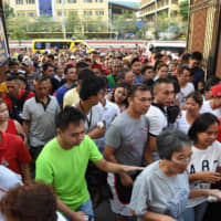 Voters rush inside as the gate opens at a polling precinct in Manila on Monday for a midterm poll. The vote was expected to strengthen President Rodrigo Duterte\'s grip on power, opening the way for him to deliver on pledges to restore the death penalty and rewrite the constitution. | AFP-JIJI
