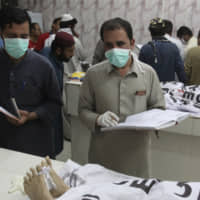 Pakistan hospital staff collect information on alleged terrorists killed by security forces, at a mortuary in Quetta, Pakistan, Thursday. Pakistani police say security forces acting on intelligence raided a militant hideout in the town of Mastung in southwestern Baluchistan province, triggering a shootout that killed many suspects. | AP