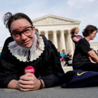 Alice Wisbiski, 22, a supporter of Ruth Bader Ginsburg, performs exercise planks in celebration of the Supreme Court associate justice\'s 86th birthday in Washington March 15. | REUTERS