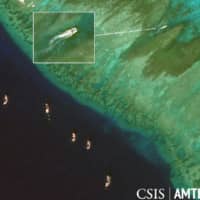 A number of Chinese clam fishing boats, which have returned to the disputed South China Sea, are seen at Scarborough Shoal, which is claimed by China, Taiwan and the Philippines, in this satellite image taken last December. | CSIS AMTI / MAXAR TECHNOLOGIES / VIA KYODO