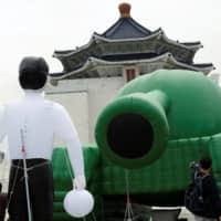 Giant balloons in the shape of a Chinese military tank and \"Tank Man\" are seen in front of Chiang Kai-Shek Memorial Hall in Taipei on Tuesday, ahead of 30th anniversary of the 1989 military crackdown on pro-democracy protesters in Beijing\'s Tiananmen Square. | REUTERS
