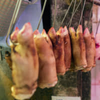 Pigs\' feet hang on display for sale at a market stall in Hong Kong on Saturday.  African swine fever, which has spread rapidly in China, has also hit neighboring Vietnam, which has culled more than 1.2 million infected farmed pigs. | BLOOMBERG