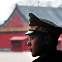 A Chinese soldier guard stands inside the Forbidden City in Beijing in this file photo taken in 2009. Tokyo has reportedly asked Beijing to have a meeting of foreign and defense ministers of the two countries. | GETTY IMAGES