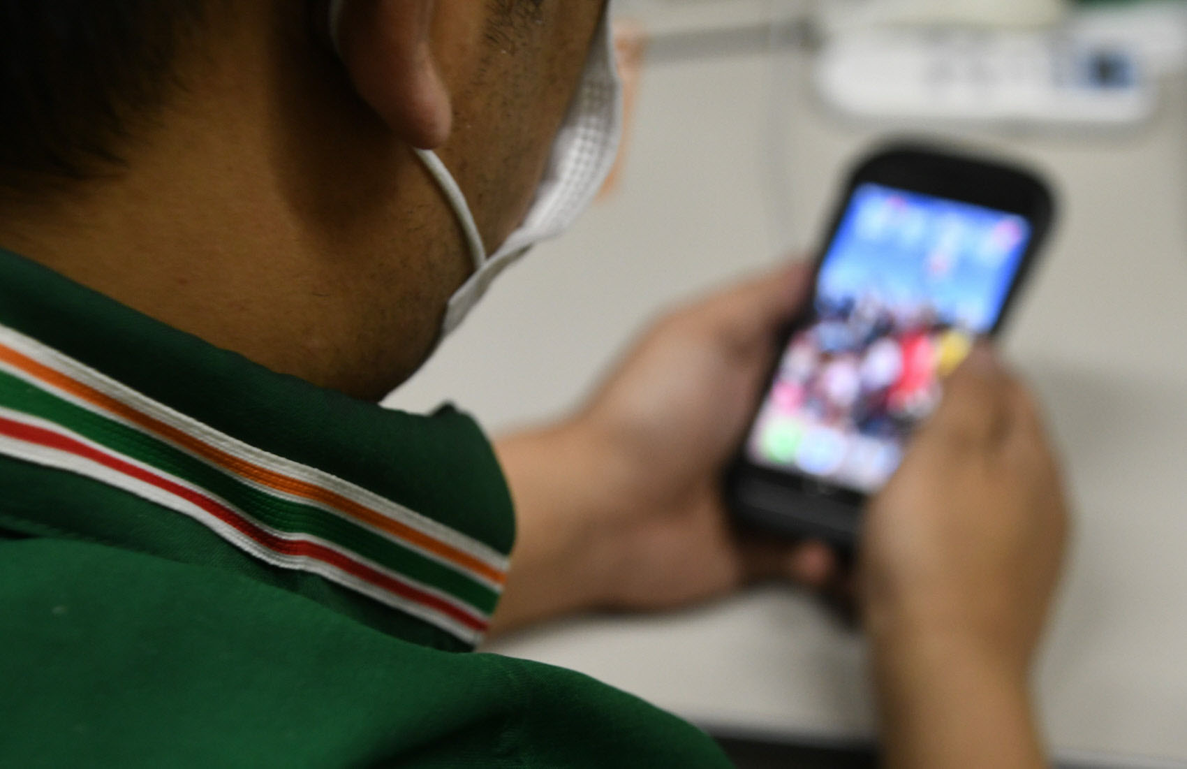 The owner of a 7-Eleven convenience store in the Chubu region looks at a photo of his family on his smartphone while taking a break before dawn in late March. | CHUNICHI SHIMBUN
