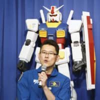 Japanese astronaut Norishige Kanai briefs reporters at a news conference in Tokyo on Wednesday about the Tokyo 2020 organizers\' plan to launch model robots from the \"Mobile Suit Gundam\" anime series into space aboard a satellite that will broadcast messages of support to athletes. | KYODO
