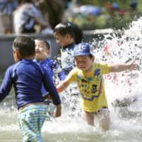 Children play in the water at a park in the city of Osaka on Saturday as temperatures exceeded 30 C in the city and in several other parts of the country. | KYODO