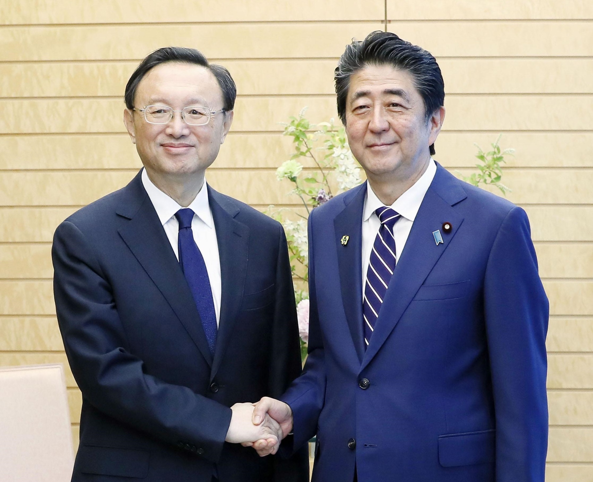 Prime Minister Shinzo Abe and high-ranking Chinese diplomat Yang Jiechi shake hands Friday at the Prime Minister's Office. | KYODO