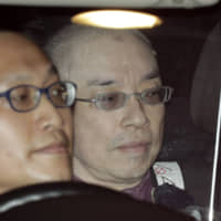 Kaoru Hasegawa (right) is taken to a police station in Tokyo on April 29. | KYODO