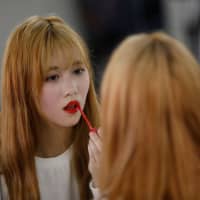 Yuho Wakamatsu, 15, who wants to become a K-pop star, adjusts her makeup during a training session in Seoul on March 12. | REUTERS