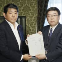 Yoshio Tezuka (left) of the Constitutional Democratic Party of Japan submits a joint motion to the House of Representatives on Friday urging Hodaka Maruyama to resign. | KYODO