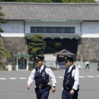 Police officers stand guard outside the Imperial Palace in Tokyo on Friday. U.S. President Donald Trump is scheduled to meet with newly crowned Emperor Naruhito and Prime Minister Shinzo Abe during a four-day visit to Japan that begins Saturday. | BLOOMBERG