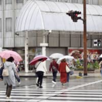 People walk in the rain in the city of  Miyazaki on Saturday. Torrential rain fell on parts of southern Kyushu the same day and, due to a damaged road on Yakushima Island, in Kagoshima Prefecture, about 200 people were still stranded as of Saturday evening. | KYODO