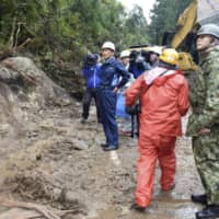 Kagoshima Gov. Satoshi Mitazono (second from left) inspects the location of a mudslide on Yakushima island on Monday, a day after hundreds of stranded hikers were rescued. | KYODO