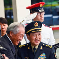 Chinese Defense Minister Wei Fenghe (right) is greeted by his Singaporean counterpart, Ng Eng Hen, during a welcoming ceremony in Singapore on Wednesday. | AFP-JIJI