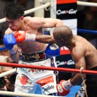 Masayuki Kuroda (left) takes a punch from Moruti Mthalane during their IBF flyweight title bout on Monday in Tokyo\'s Korakuen Hall. | AFP-JIJI