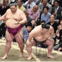 Ozeki Takakeisho reacts after injuring his right knee on Wednesday during his victory over Mitakeumi at the Summer Grand Sumo Tournament. KYODO | AFP-JIJI