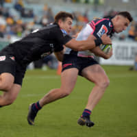The Sunwolves\' Gerhard van den Heever (left) tackles the Brumbies\' Tom Banks during their Super Rugby match on Sunday in Canberra. | AFP-JIJI