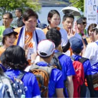 Former Olympic judo silver medalist Shinichi Shinohara (second from left) interacts with participants during a public walking event near Tokyo Bay on Saturday. | KYODO