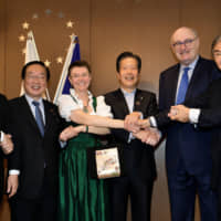 European Union Ambassador to Japan Patricia Flor (third from left) and European Commissioner for Agriculture and Rural Development Phil Hogan (second from right) hold hands with (from left) Acting Chairman of the Japan-EU Parliamentary League of Friendship Masaharu Nakagawa, Reconstruction Minister Hiromichi Watanabe, Komeito leader Natsuo Yamaguchi and Chair of the Japan-EU Parliamentary League of Friendship Nobuteru Ishihara at the Europe Day reception held at the Europa House on May 9. | YOSHIAKI MIURA