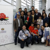 Los Kjarkas poses with Angela Karin Ayllon Quisbert, Bolivian charge d\'affaires ad interim (center row, second from right); Hidejiro Mimura, president of the association of cultural exchange between Latin America and Japan (center row, left); and members of the Bolivian embassy staff with family. | PHOTO COURTESY OF BOLIVIA EMBASSY