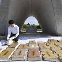 Documents bearing the names of 314,118 people who lost their lives due to the 1945 atomic bombing of Hiroshima dry in the sun on Wednesday in front of the memorial cenotaph in Hiroshima Peace Memorial Park, after being taken out of underground storage. | KYODO