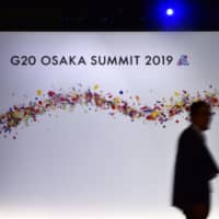 A man walks past a sign at the venue for the G20 Osaka Summit in Osaka on Wednesday ahead of the start of the summit. | AFP-JIJI