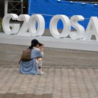 A woman takes a picture of a G20 Osaka design set up outside the venue for the G20 Osaka Summit Wednesday. | AFP-JIJI