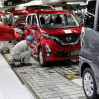 A worker assembles a minicar on the production line at the Mitsubishi Motors Mizushima plant in the city of Kurashiki, Okayama Prefecture. | BLOOMBERG